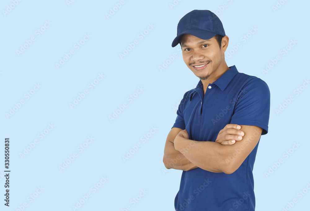 Delivery service concept. Portrait delivery man standing with arms crossed on blue background. looking at camera. Delivery service concept. Portrait delivery man standing with arms crossed on blue background. looking at camera.