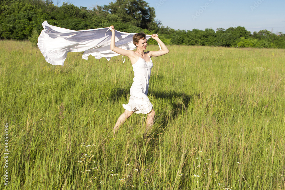 A girl in a white dress, runs across the field, and holds a white cloth in her hands A girl in a white dress, runs across the field, and holds a white cloth in her hands