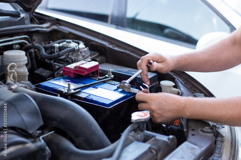 repair and installation of the battery under the hood of the car Stock