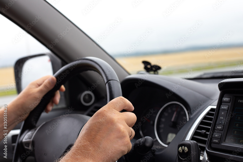 man's hands hold the steering wheel of a car