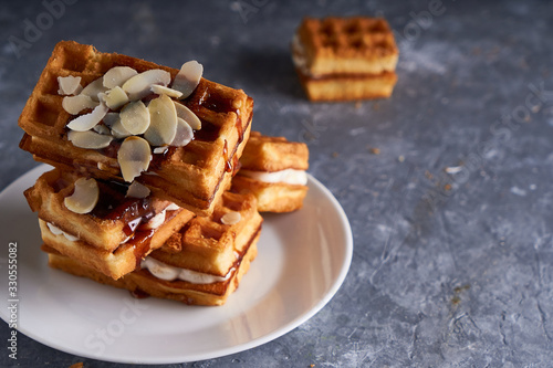 Photography delicious homemade Vienna waffles with syrup and almond crumbs served on a gray