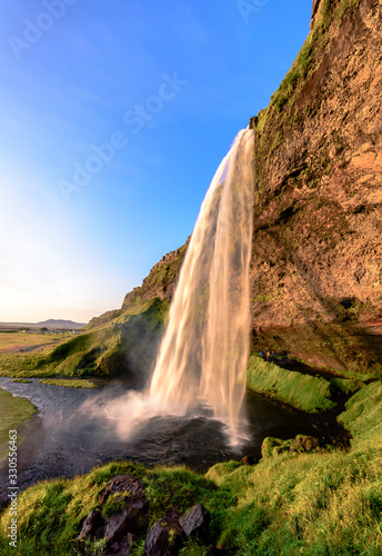 Beautiful Seljalandsfoss Waterfall during golden hour - portrait format, Sudurland, Iceland