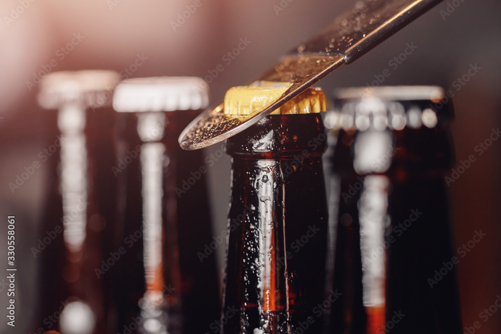 Row brown ice cold beer bottle with water drops and metal opener cap, dark background - obrazy, fototapety, plakaty 