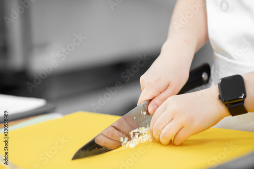 Hands woman chef cut knife with garlic and onion on cutting board closeup