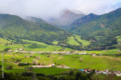 Scenic panorama of farms, forest, mountains, and clouds with lush green landscape