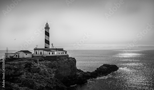 a lonely lighthoase on the coastline of the Island of Mallorca guifing since decades the safe way to the port  captured in monochrome black and hite 