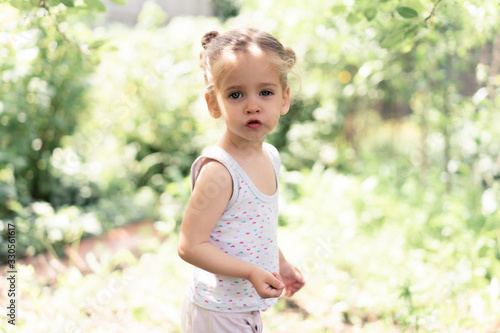 Little Caucasian girl, two years old, gathering unripe cherries in orchard