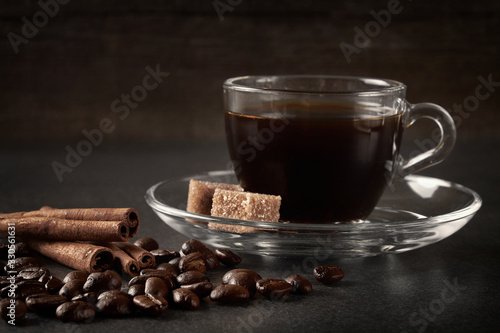 glass Cup of coffee beans with cinnamon and sugar on a dark wooden background