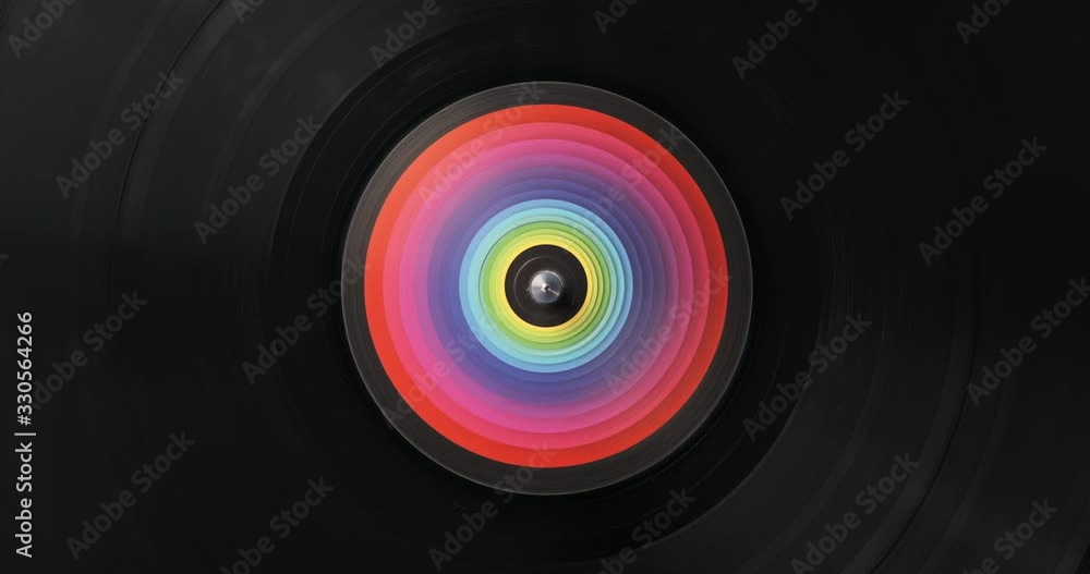 Black vinyl record DJ player. Black vinyl background with color spectrum label in center. Rotating plate close-up. Consignment. Loop. Macro Top view. Popular styles of disco from 60s, 70s, 80s, 90s Black vinyl record DJ player. Black vinyl background with color spectrum label in center. Rotating plate close-up. Consignment. Loop. Macro Top view. Popular styles of disco from 60s, 70s, 80s, 90s