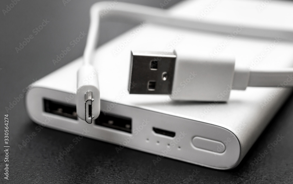 Powerbank for charging mobile devices with cable on black desk. Powerbank for charging mobile devices with cable on black desk.