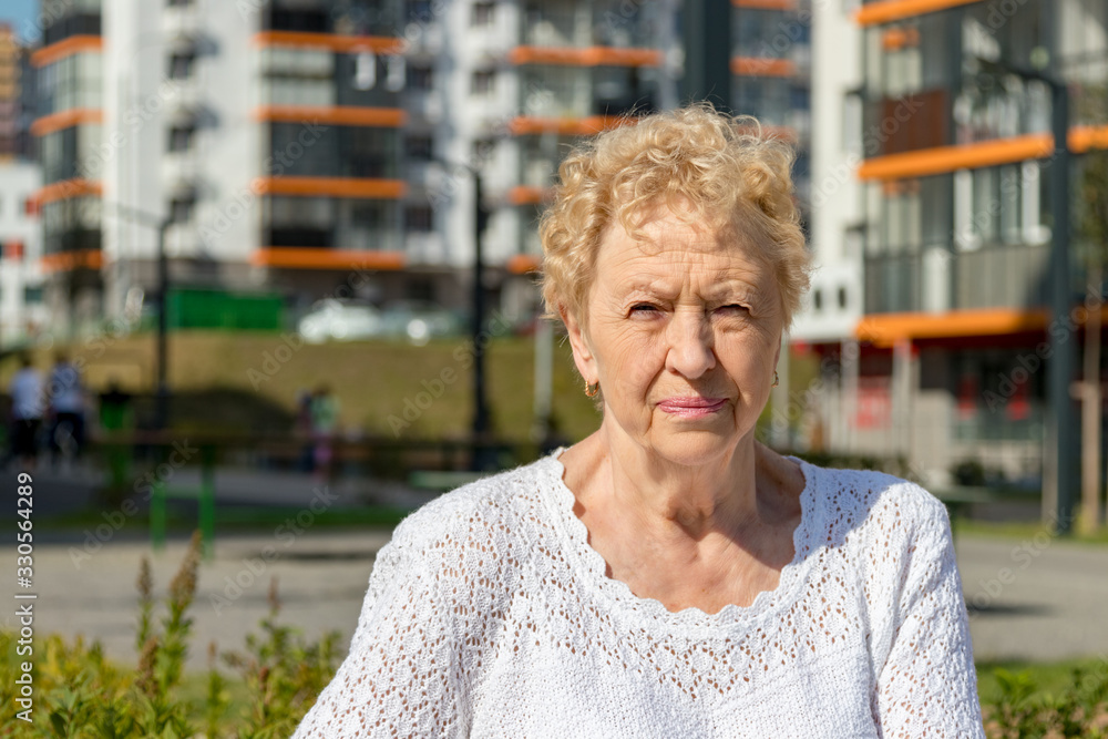 Relaxed elder woman sitting on a bench looking at camera and smiling. Happy old age concept Relaxed elder woman sitting on a bench looking at camera and smiling. Happy old age concept
