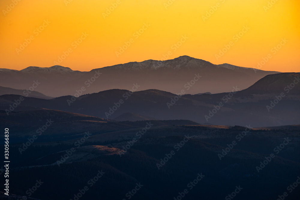 Orange and yellow sunset with mountains silhouettes. Gradient vivid nature background.