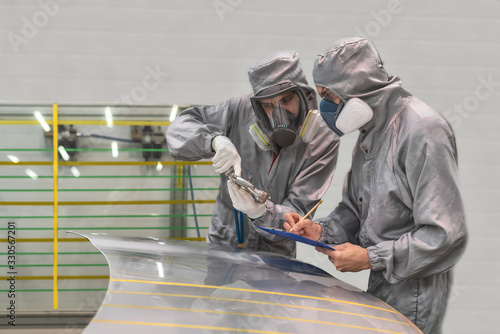 Employee of the paint shop of automobile factory conducts training on painting body parts