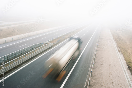 Tank truck rides fast on a highway in a misty cold day. Concept of road safety problem.