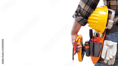 View from behind, electrician holds multimeter tester in hand, helmet with protective goggles. Construction industry, electrical system. Isolated on a white background.