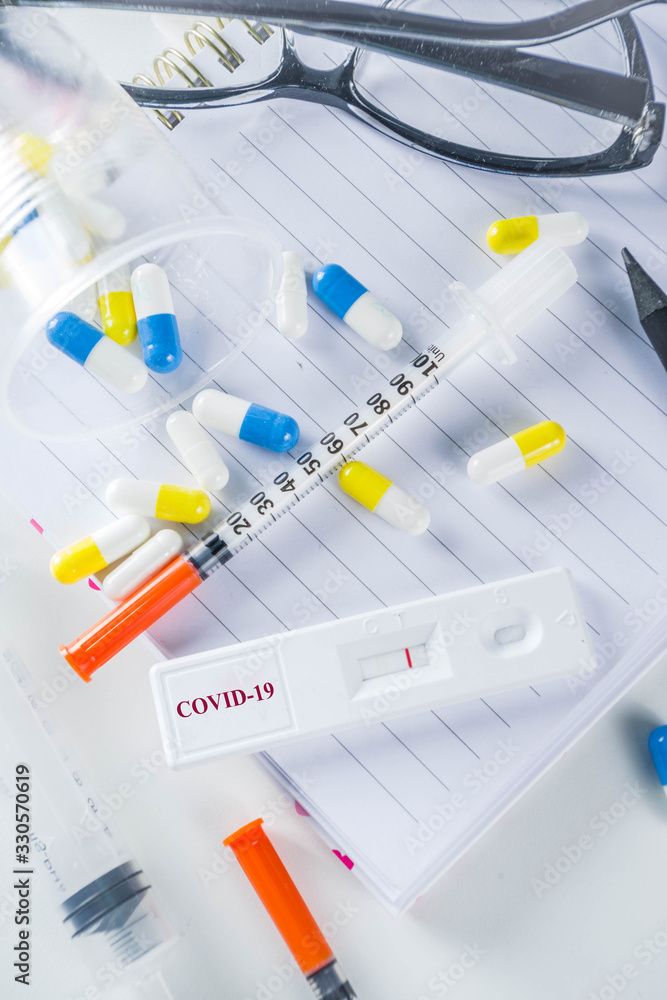 Fototapeta premium Worldwide coronavirus epidemic concept. Pandemic COVID-19, 2019-nCoV. Laboratory test strip for antibody or sars-cov-2 virus disease. In doctor hands. With pills, vaccination syringes, notebook.