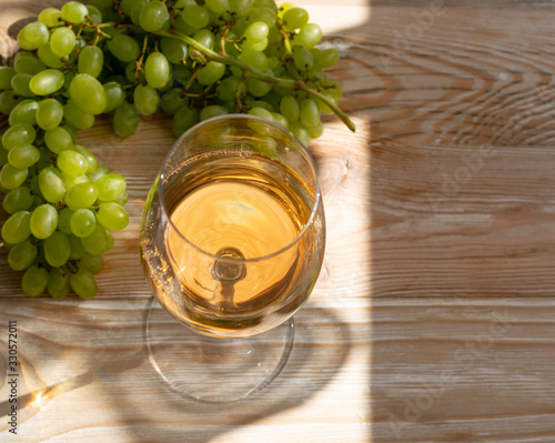 White Wine Glass on Ripe Green Grapes Background in Sunny Day