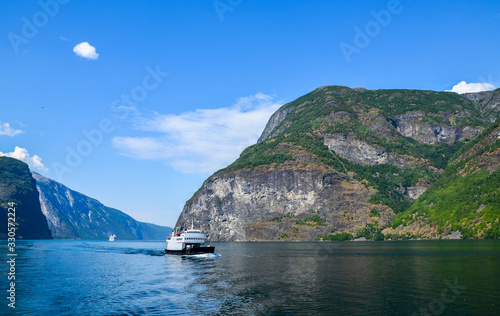 A tourist ship  and  cruise liner are sailing on the Sognefjord, which is one of the most beautiful fjords and the largest in Europe and second largest in the world. Norway photo