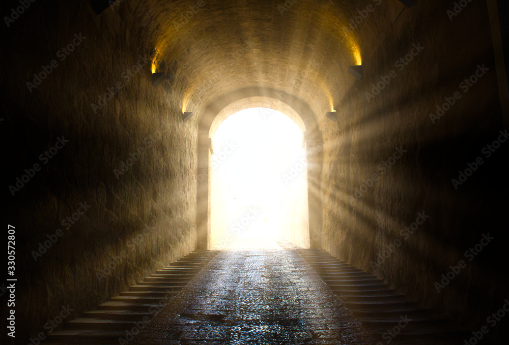 A bright yellow glowing light breaking through at the end of a dark tunnel