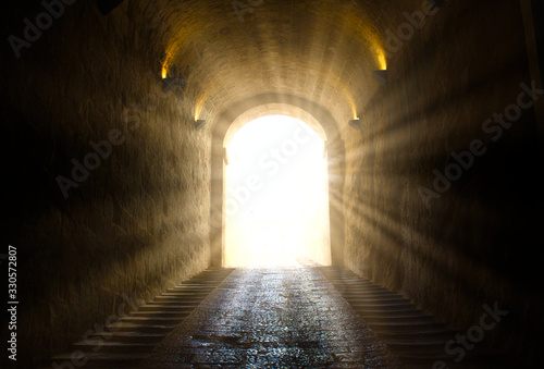 Fototapeta A bright yellow glowing light breaking through at the end of a dark tunnel