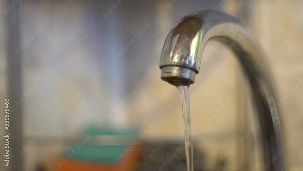 Chrome tap in the kitchen. Water flows and the tap closes. Water pipes. Clean source. Filtered fluid. Macro. Close-up. Chrome tap in the kitchen. Water flows and the tap closes. Water pipes. Clean source. Filtered fluid. Macro. Close-up.