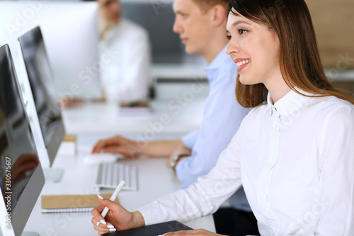 Wallpaper Mural Cheerful smiling asian businesswoman headshot at work in modern office. Casual dressed female entrepreneur using pc computer while sitting with diverse colleagues at the background. Multi ethnic Torontodigital.ca