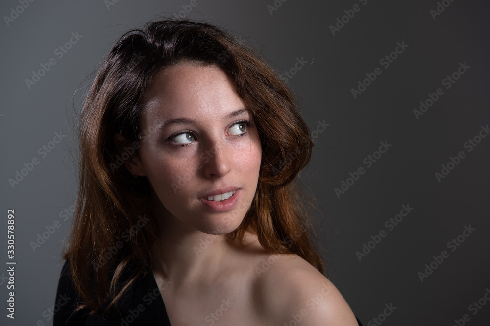 Portrait of attractive young women. Brunette female model with bared shoulder looking up. Isolated on grey background... Portrait of attractive young women. Brunette female model with bared shoulder looking up. Isolated on grey background...