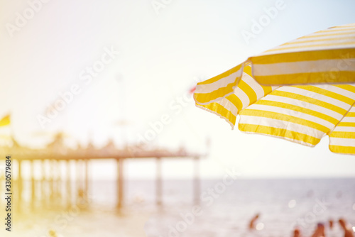 there is a large yellow-white striped umbrella on the beach