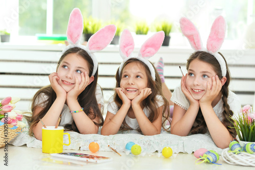Cute girls wearing rabbit ears decorating Easter eggs