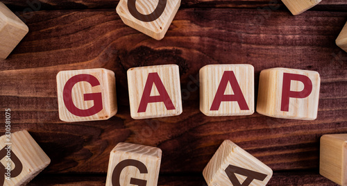 Foto GAAP (Generally Accepted Accounting Practice) word on wooden cubes on a dark wood background