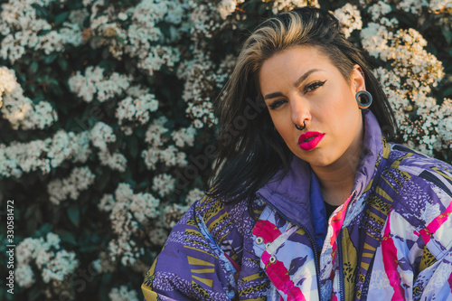 Mujer joven con gorro negro y chaqueta de colores delate de flores blancas photo