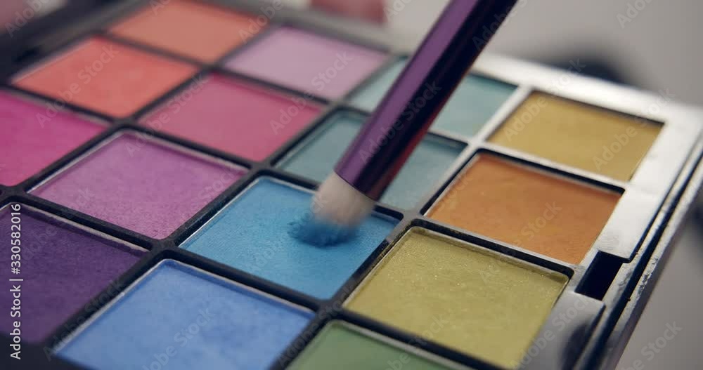 Make-up artist dips a brush in blue palette Make-up artist dips a brush in blue palette
