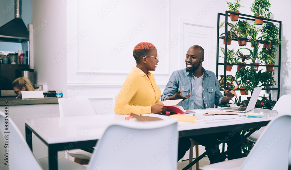 Black serious coworkers talking in cafe