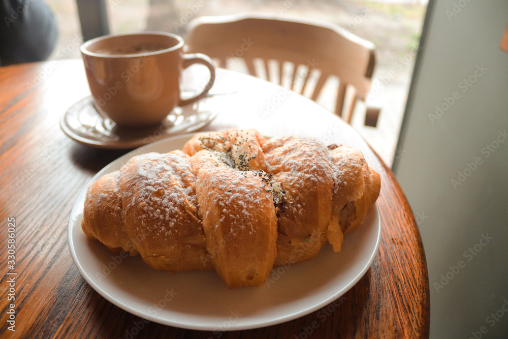 Food and drink concept. Croissant with cup of coffee on wooden table. Delicious French breakfast. Tasty food. Food and drink concept. Croissant with cup of coffee on wooden table. Delicious French breakfast. Tasty food.