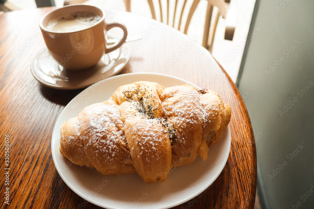Food and drink concept. Croissant with cup of coffee on wooden table. Delicious French breakfast. Tasty food. Food and drink concept. Croissant with cup of coffee on wooden table. Delicious French breakfast. Tasty food.