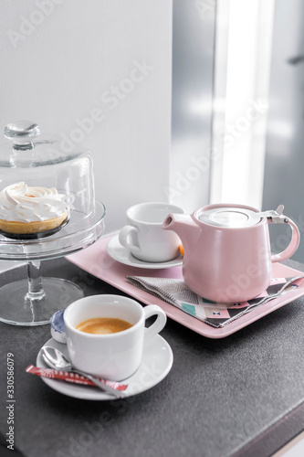 Coffee pot and cups setup on a tray and dessert cake in bright light mood