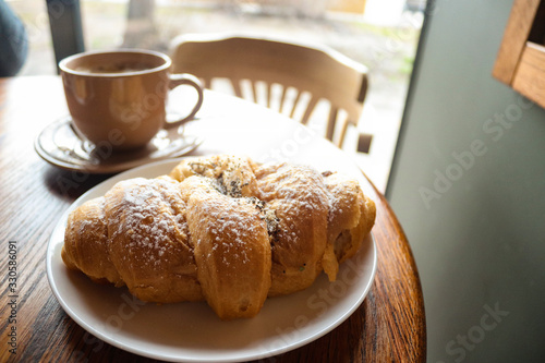 Food and drink concept. Croissant with cup of coffee on wooden table. Delicious French breakfast. Tasty food.