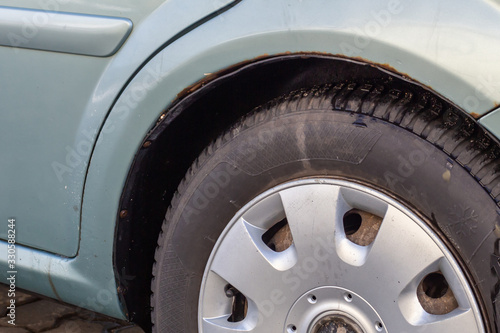 Rust on the body of a blue car. Rust hole on old worn painted metal surface. Corrosion of the vehicle metal due to accident