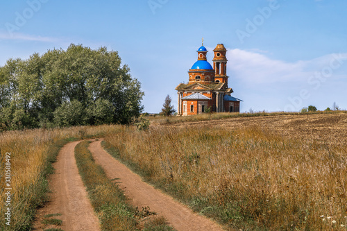 Abandoned church in the field (built in 1822), empty dirt road. Russia, Lipetsk region. photo