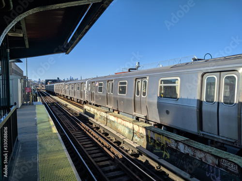 Train at platform in long Island, New York, Queens, with the skyline in the background in a sunny clear day photo