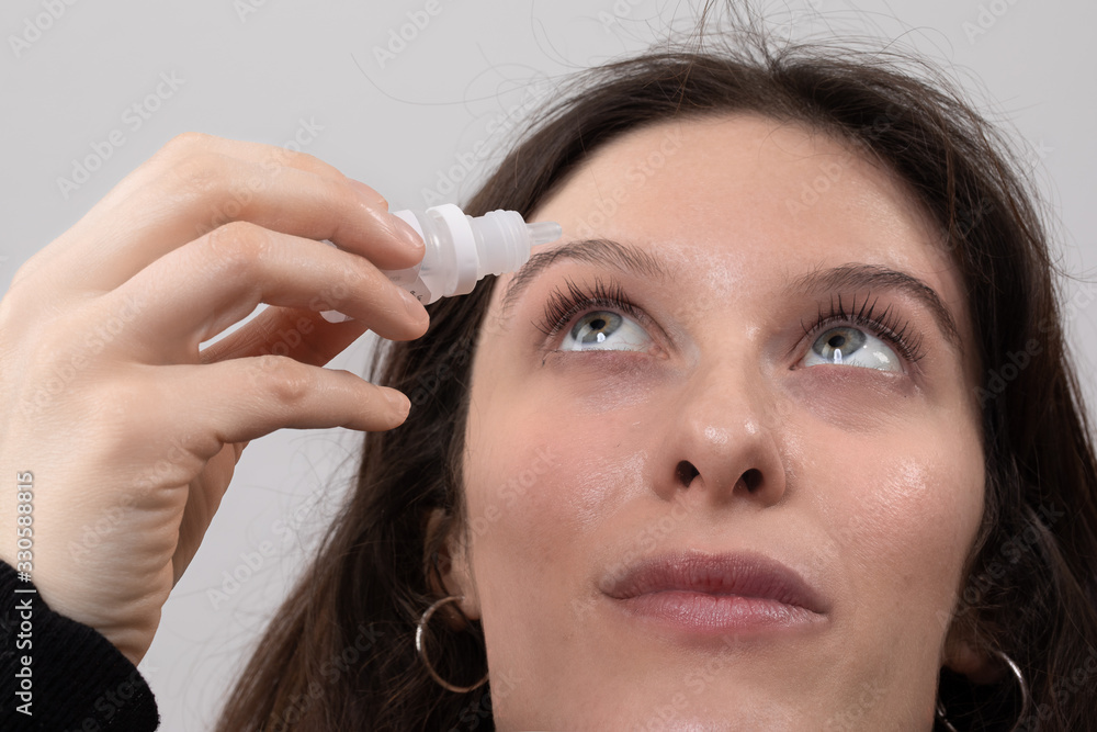 Young white woman applying eye drops for dry eye relief Young white woman applying eye drops for dry eye relief
