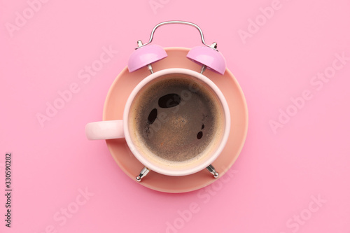 Creative alarm clock made with cup of coffee on color background photo