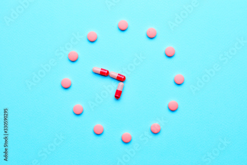 Creative clock made of pills on color background