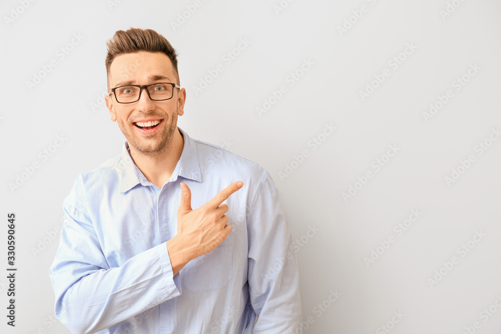 Portrait of handsome young man showing something on light background