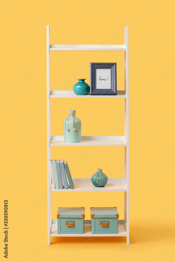 Fototapeta premium Shelving unit with decor on color background