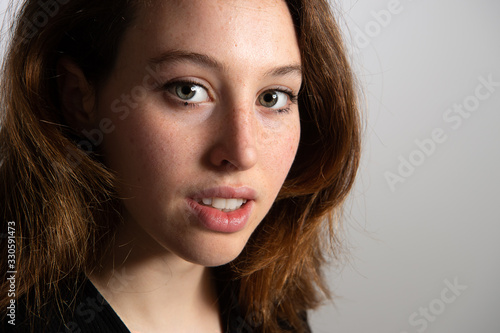 Headshot of a pretty young female with cute freckles and beautiful green eyes