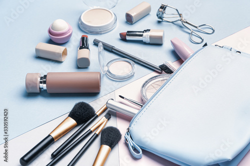 Bag with makeup accessories and decorative cosmetics on color background