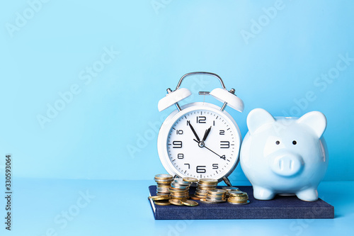 Alarm clock, piggy bank and coins on color background. Time management concept photo