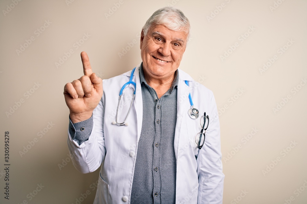 Senior handsome hoary doctor man wearing coat and stethoscope over white background showing and pointing up with finger number one while smiling confident and happy. Senior handsome hoary doctor man wearing coat and stethoscope over white background showing and pointing up with finger number one while smiling confident and happy.