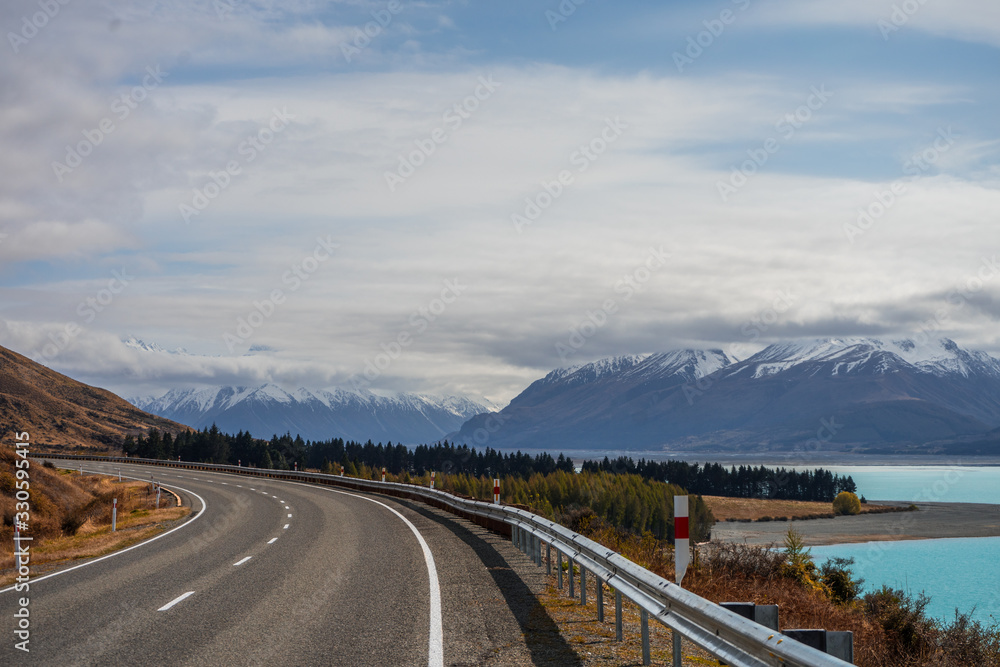 Asphalt road with snowy mountains in the background in Mount Cook, New Zealand Asphalt road with snowy mountains in the background in Mount Cook, New Zealand